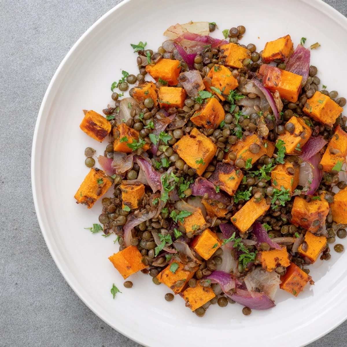 Golden root vegetables and lentils in Warm Hearth Vegan Side Dish, garnished with fresh parsley.