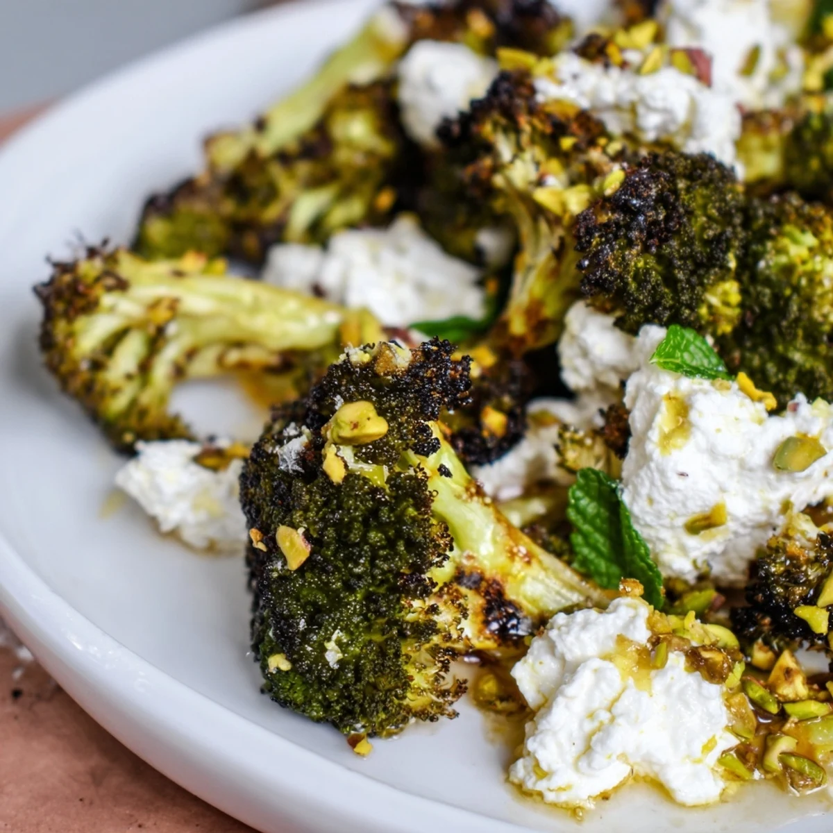 Creamy whipped feta spread topped with hot honey roasted broccoli, garnished with chopped pistachios and fresh mint.