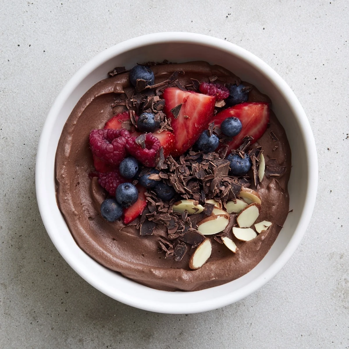 Creamy Chocolate Avocado Protein Mousse in a glass with fresh berries and a chocolate garnish.