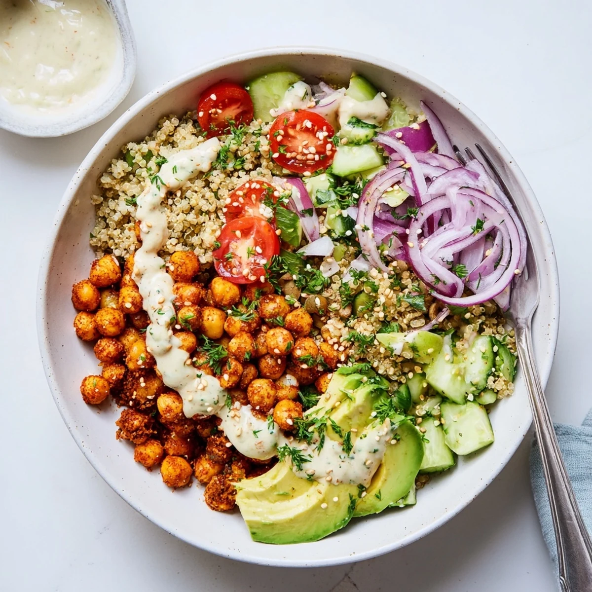 A vibrant serving of Lemon Tahini Chickpea and Quinoa-Style Cauliflower Bowl topped with tomatoes and sesame seeds.