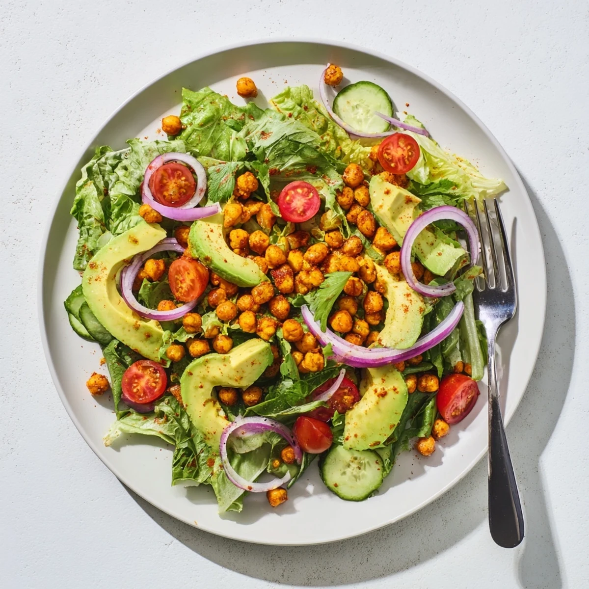 Golden chickpeas seasoned with chili and lime garnishing vibrant avocado salad with fresh vegetables