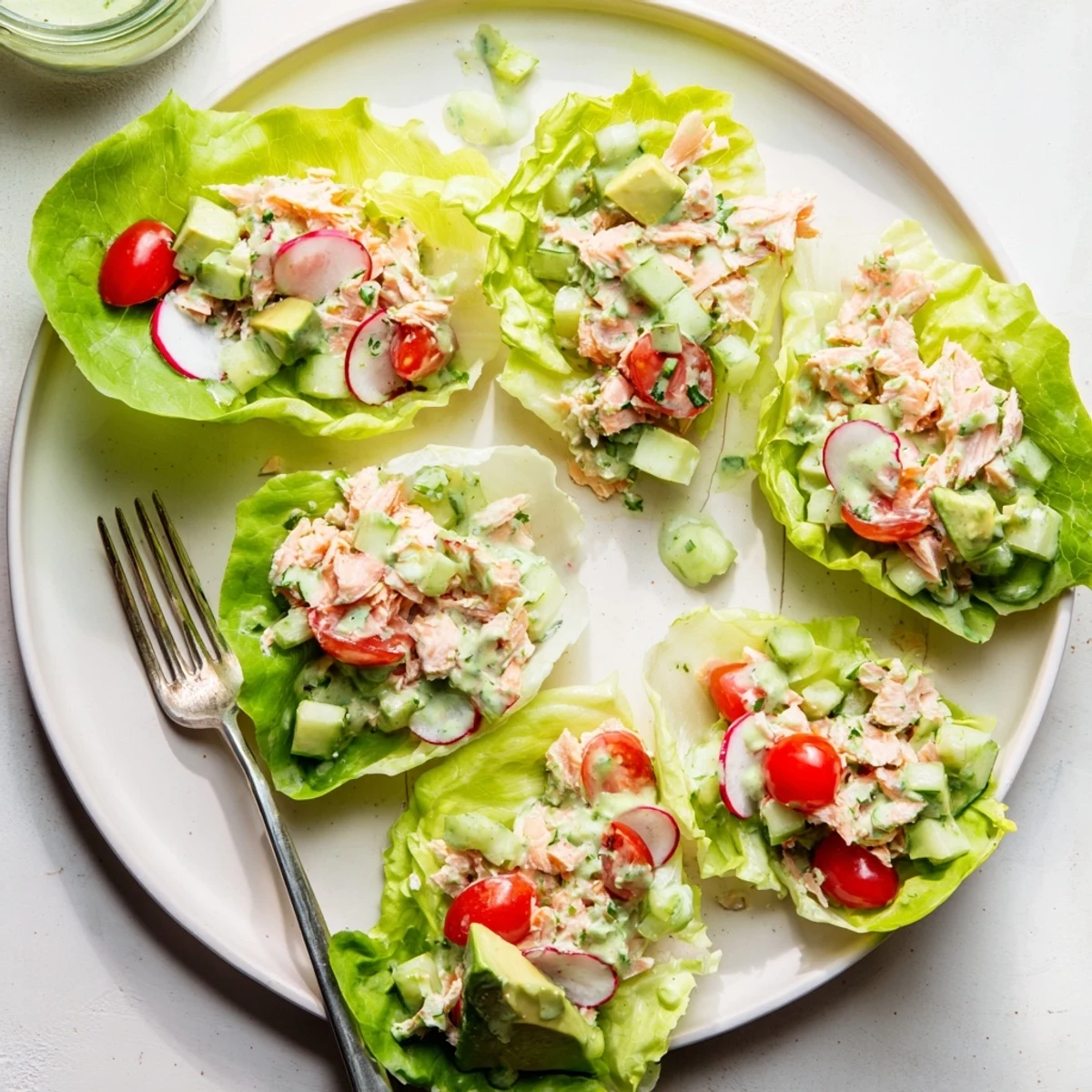 Flaky salmon and vibrant vegetables tossed in tangy green goddess dressing inside crunchy lettuce cups