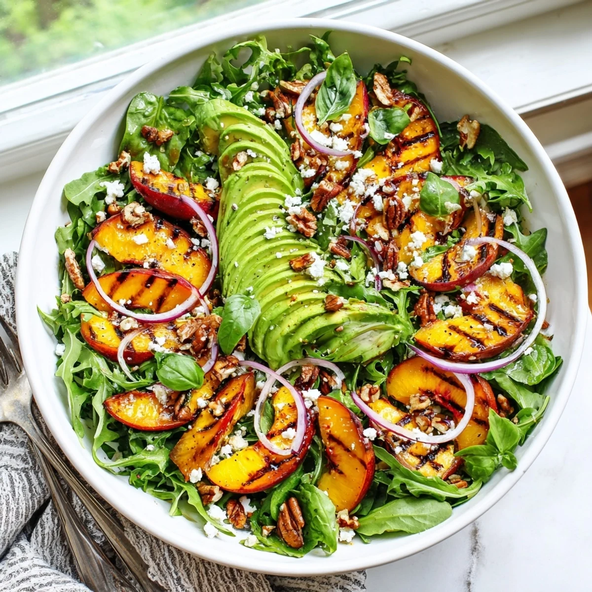 Colorful bowl of sweet grilled peaches, buttery avocado slices, and crisp arugula dressed in citrus vinaigrette