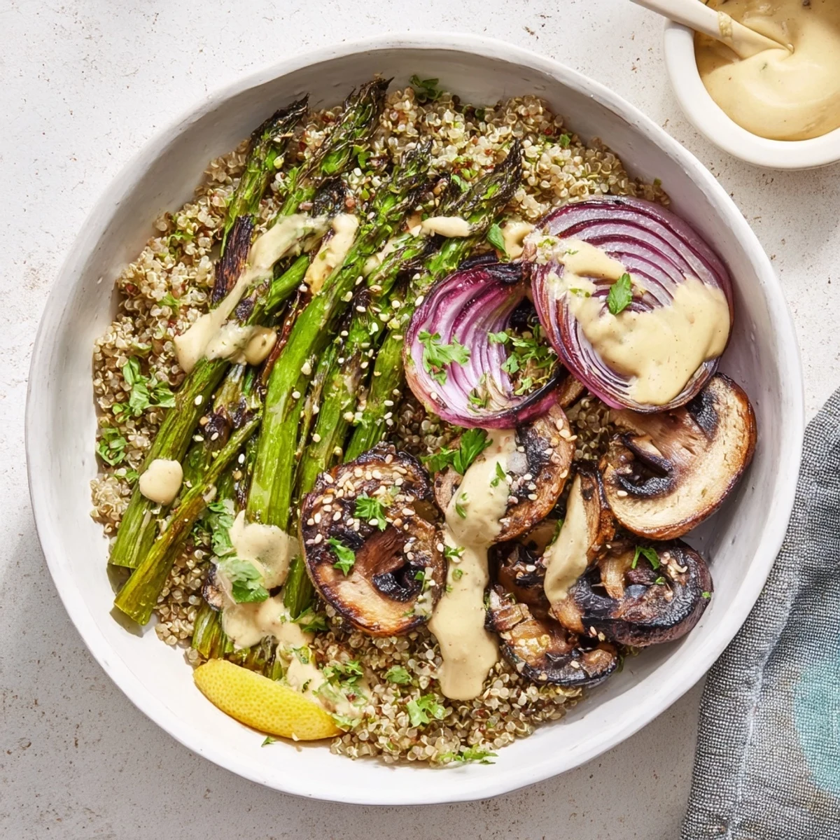 Healthy vegetable bowl with grilled asparagus and mushrooms topped with zesty tahini dressing