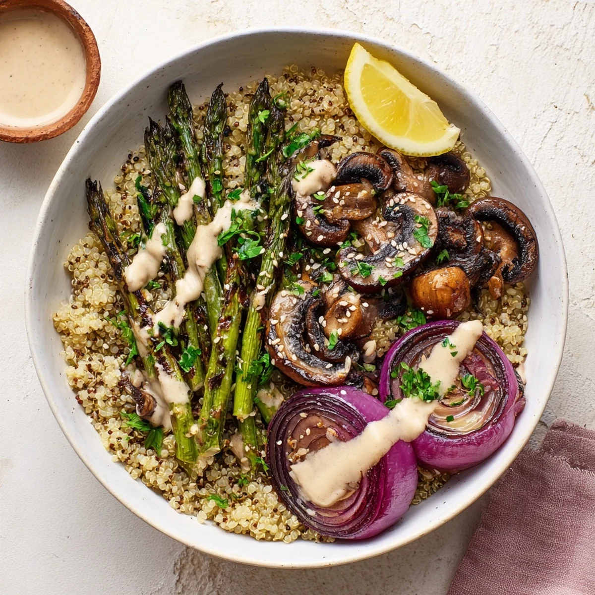 Vegan grain bowl featuring smoky grilled asparagus mushrooms drizzled with creamy lemon tahini sauce