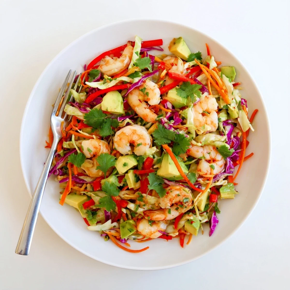 Plated avocado lime shrimp and cabbage crunch salad topped with tender spiced shrimp, diced avocado, and bright cilantro garnish