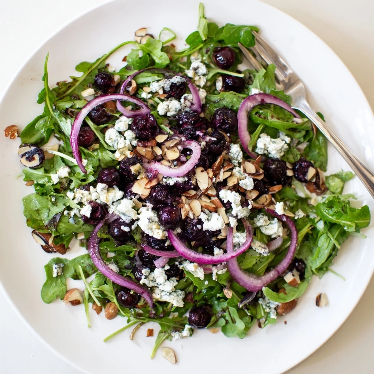Fresh roasted blueberry and arugula salad topped with creamy goat cheese and crunchy maple almonds