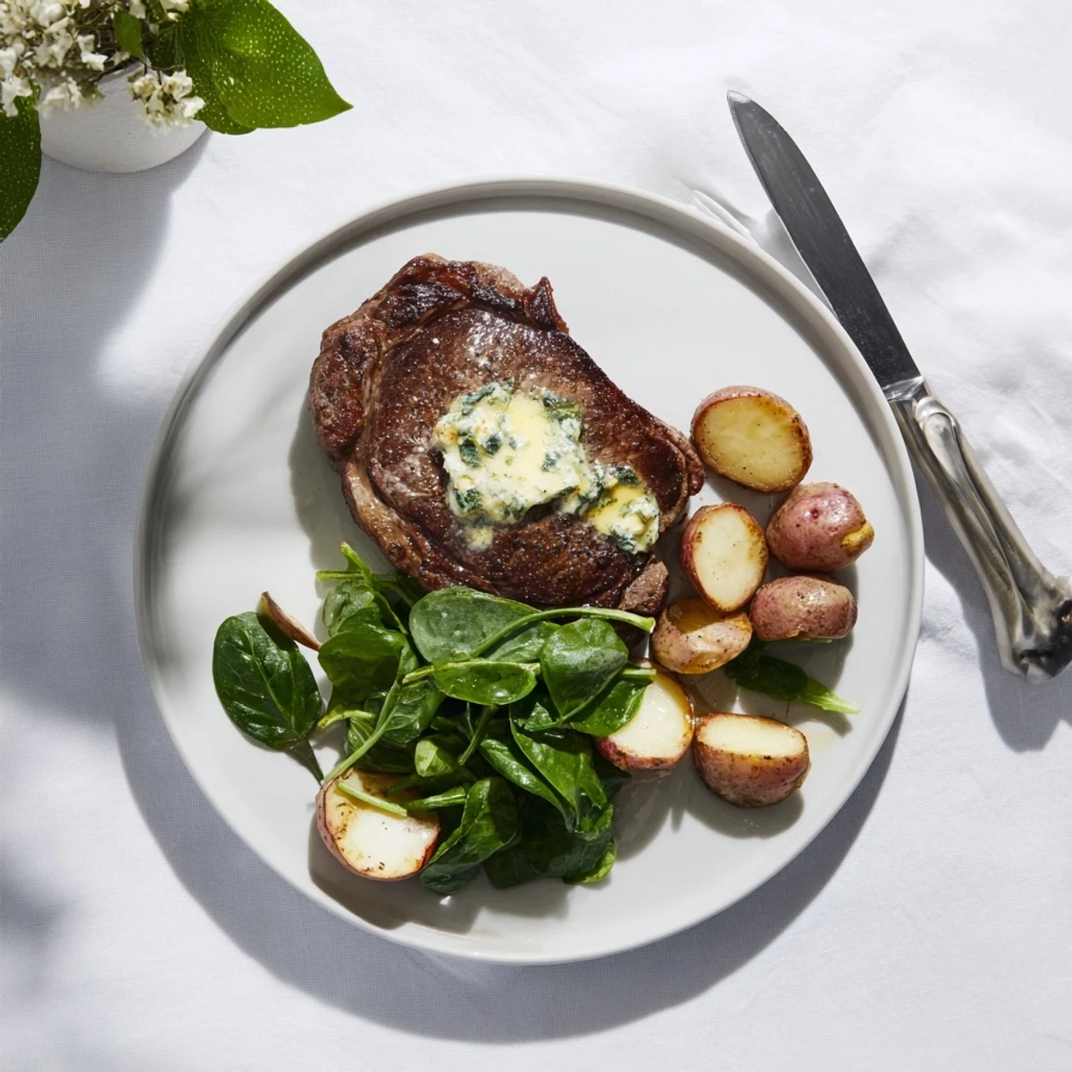 Succulent garlic butter steak with roasted radishes and wilted greens on a white plate