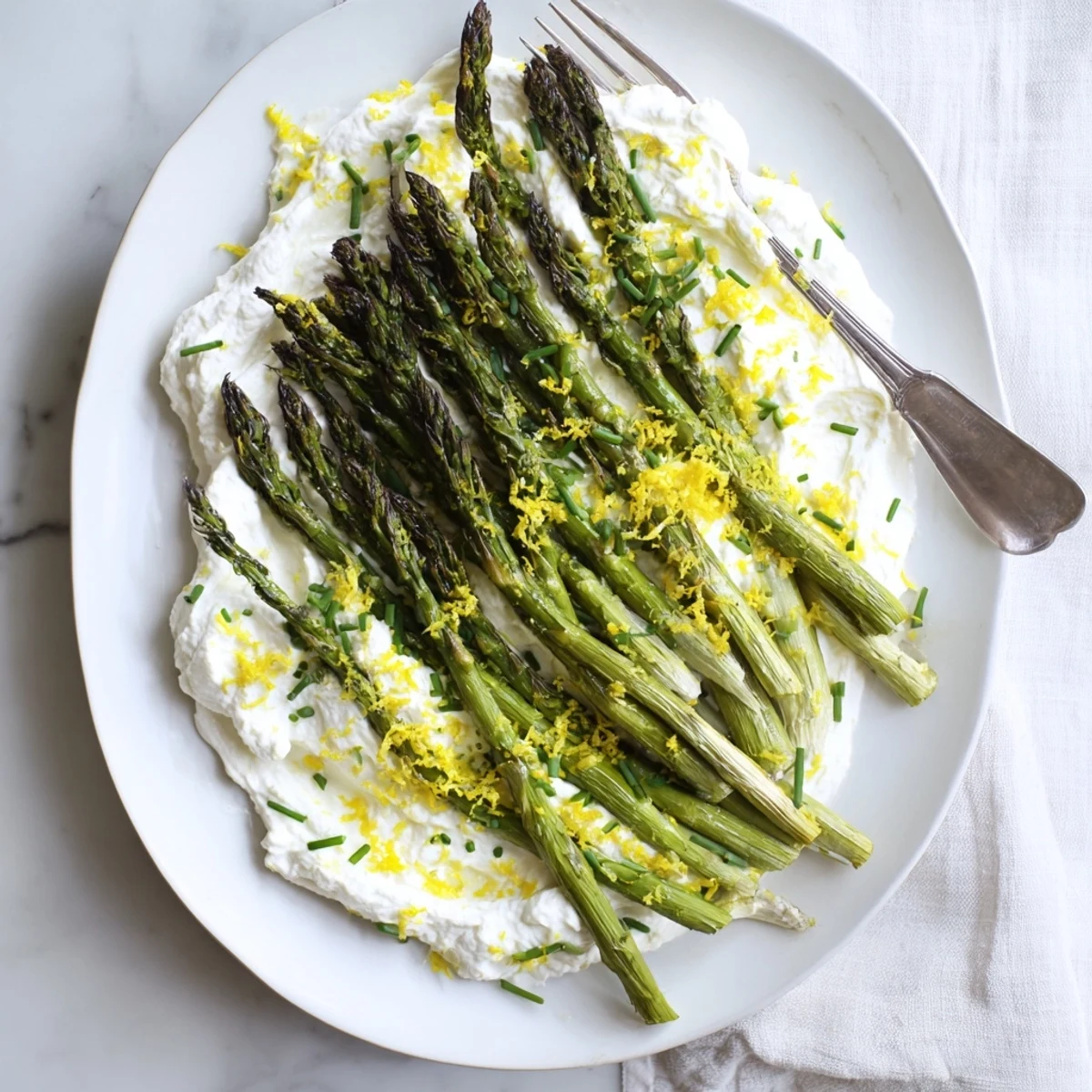 Vibrant green asparagus spears drizzled with olive oil alongside zesty lemon ricotta cream on a rustic wooden board