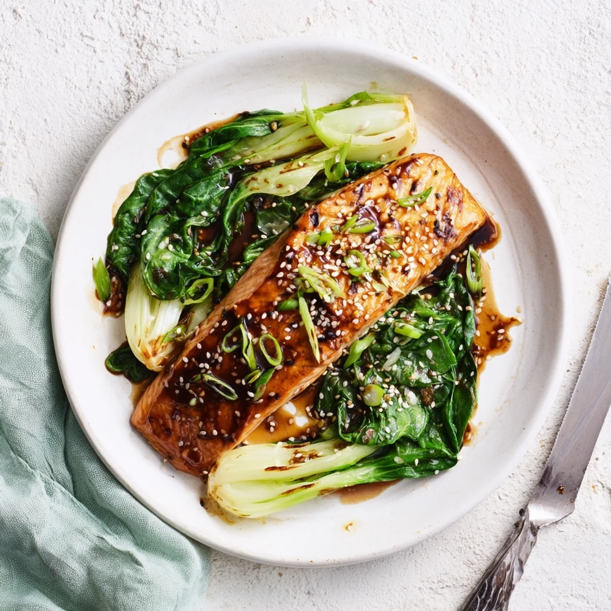Baked miso maple glazed salmon with caramelized edges served over tender wilted Asian greens and sesame seeds