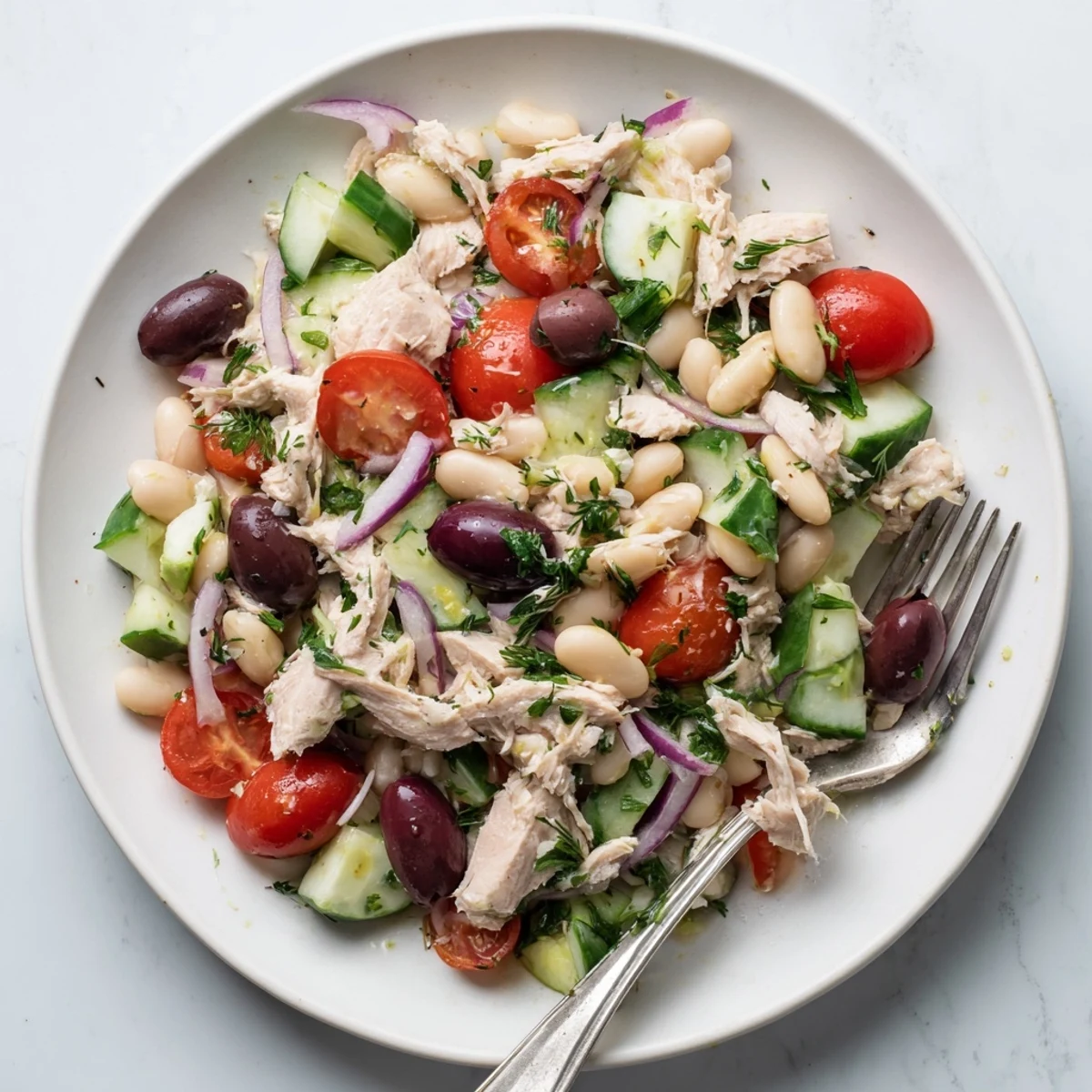 Protein-packed tuna salad featuring creamy cannellini beans, cherry tomatoes, cucumber, and bright parsley and basil garnish