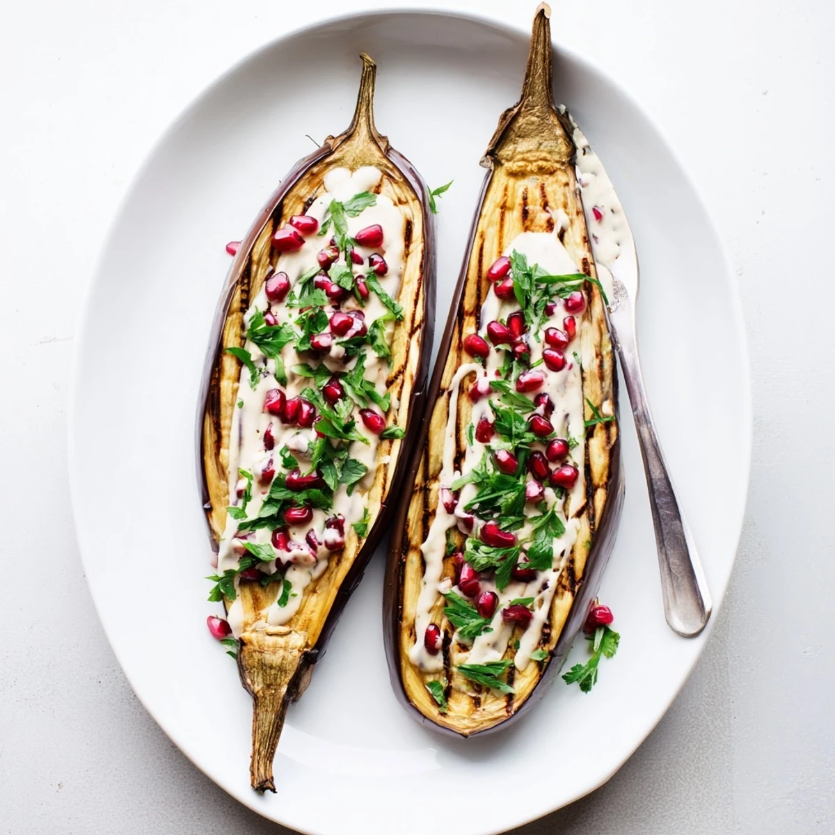 Silky roasted eggplant with tahini sauce topped with fresh parsley and bright pomegranate arils