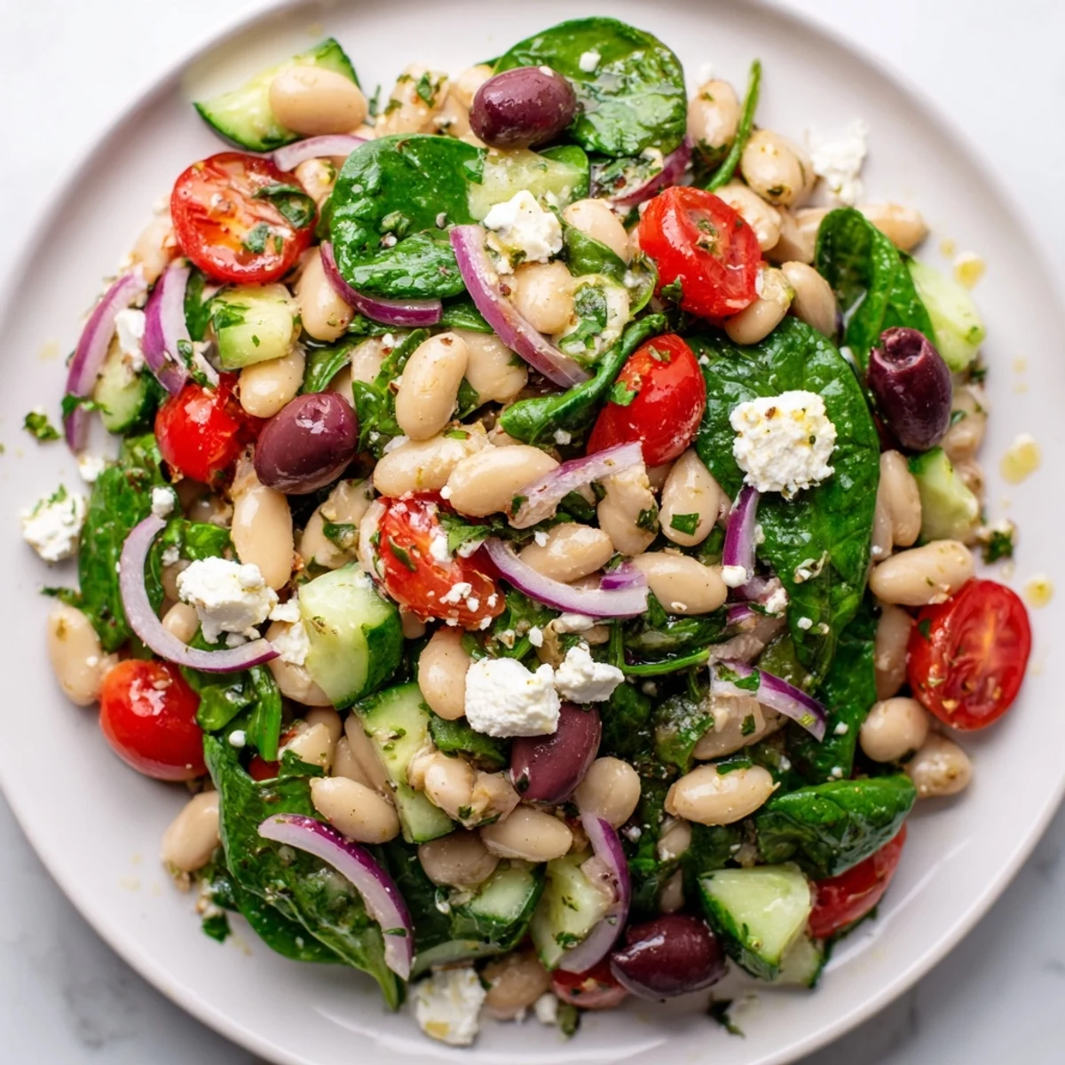 Fresh Mediterranean white bean and spinach salad with lemon dressing and colorful vegetables in a white bowl