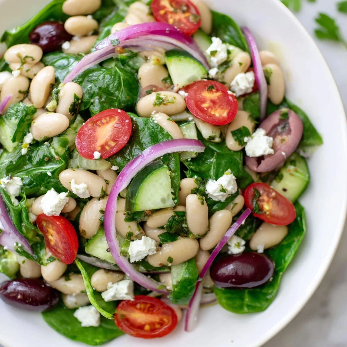 Zesty Mediterranean white bean and spinach lemon salad served with crisp cucumbers and parsley garnish for a light healthy meal