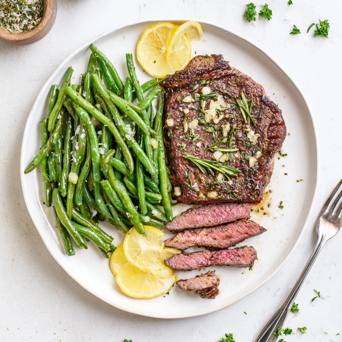 Cast-iron seared Garlic Herb Steak with Roasted Green Beans and Lemon, parsley garnish